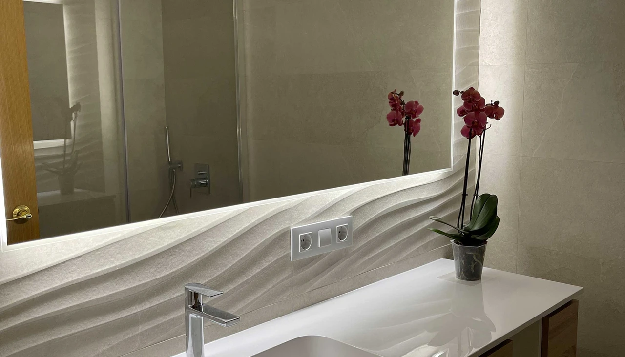 Reforma de baño con espejo retroiluminado y orquídea