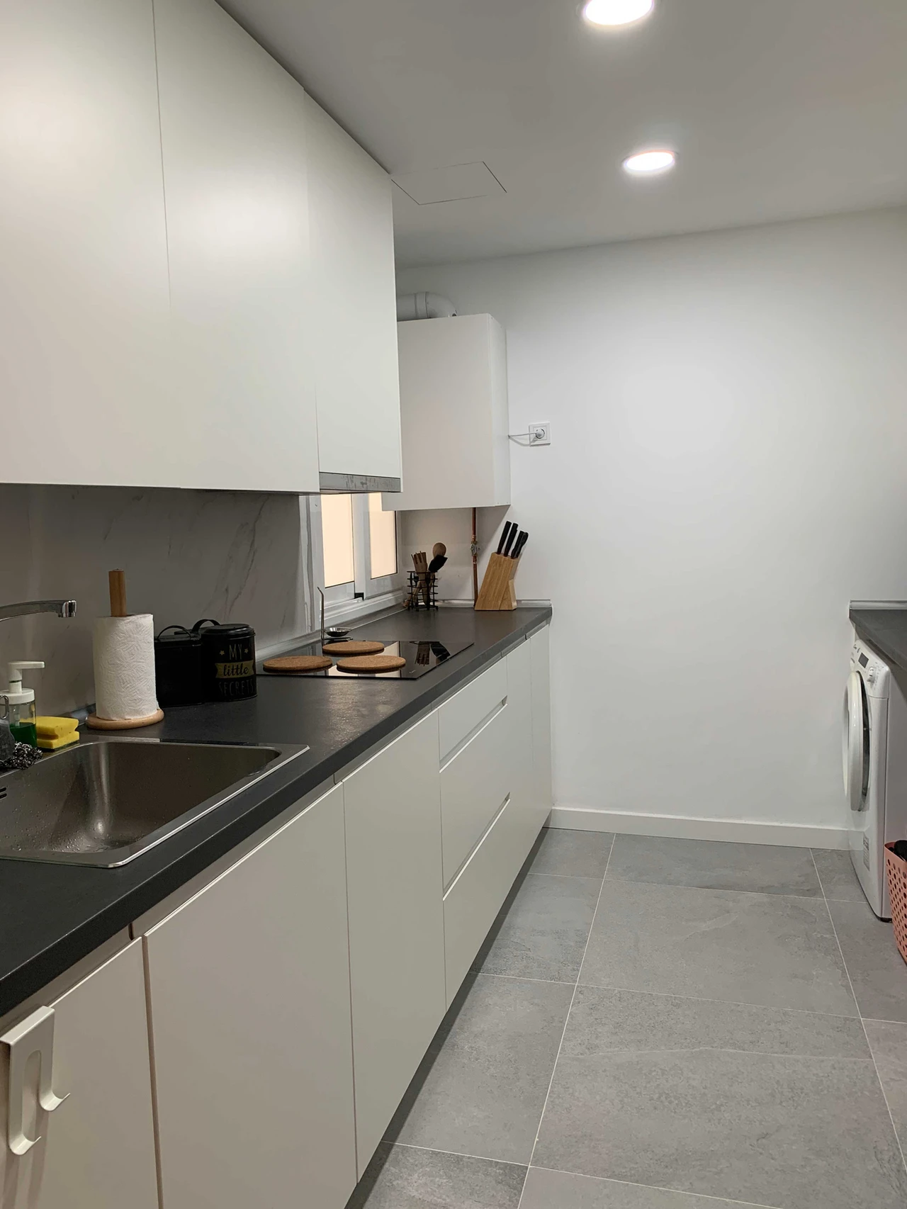 Cocina blanca con encimera negra y zona de lavado