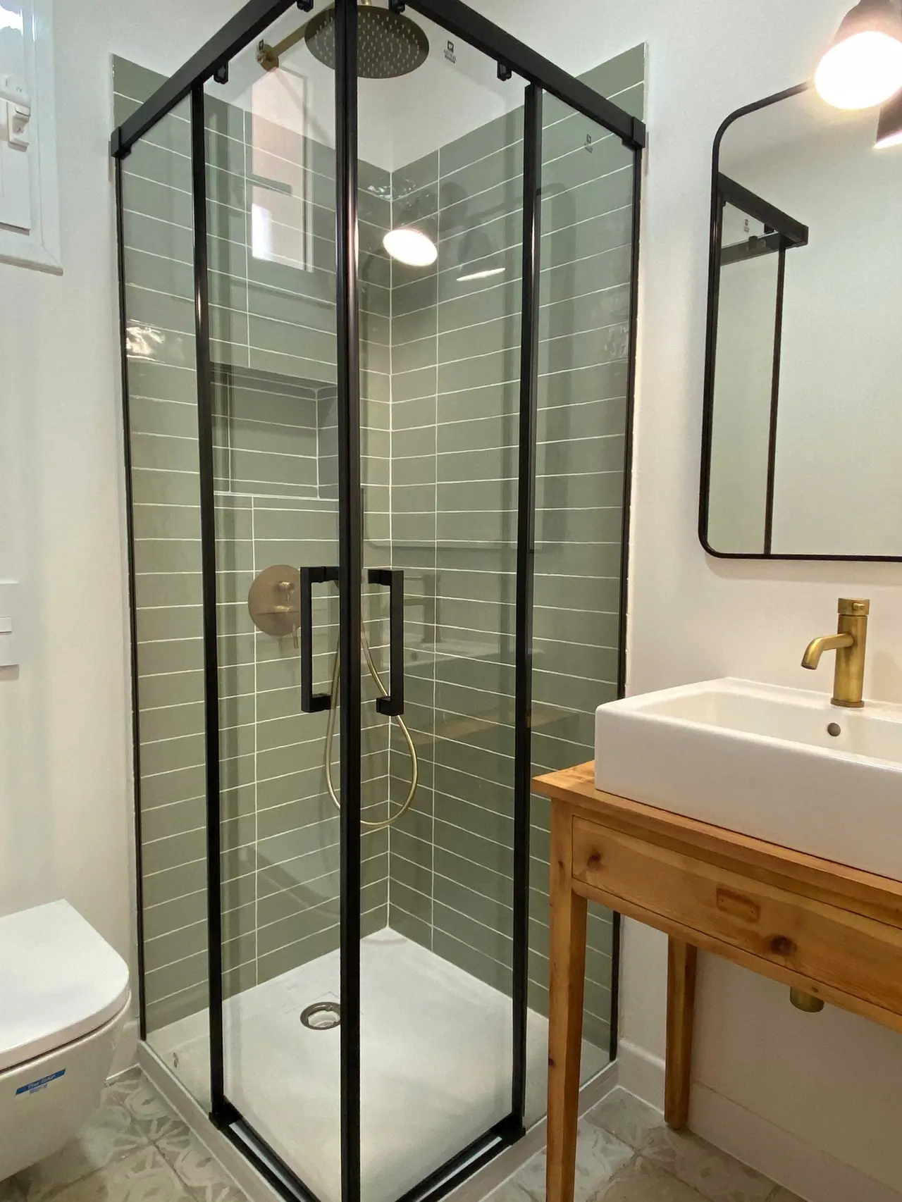Ducha con mampara negra y lavabo sobre mueble de madera