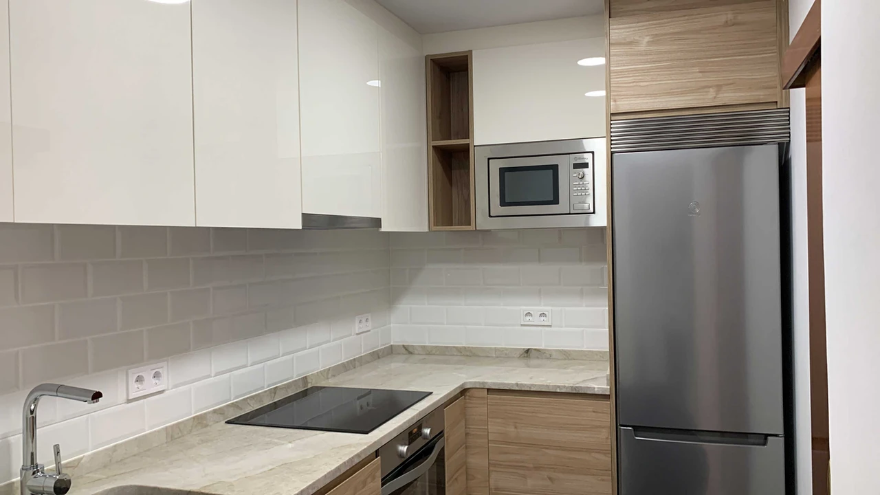 Cocina blanca con detalles en madera y nevera inoxidable