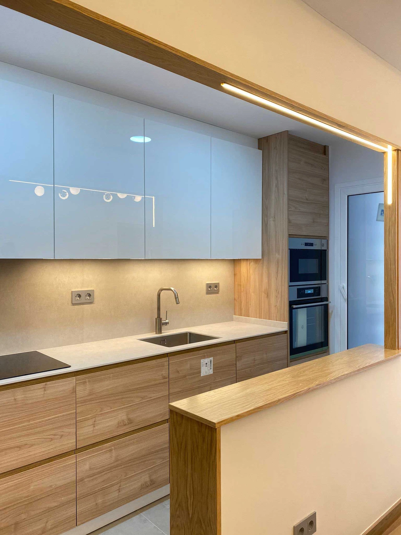 Cocina con muebles azules, madera e iluminación LED