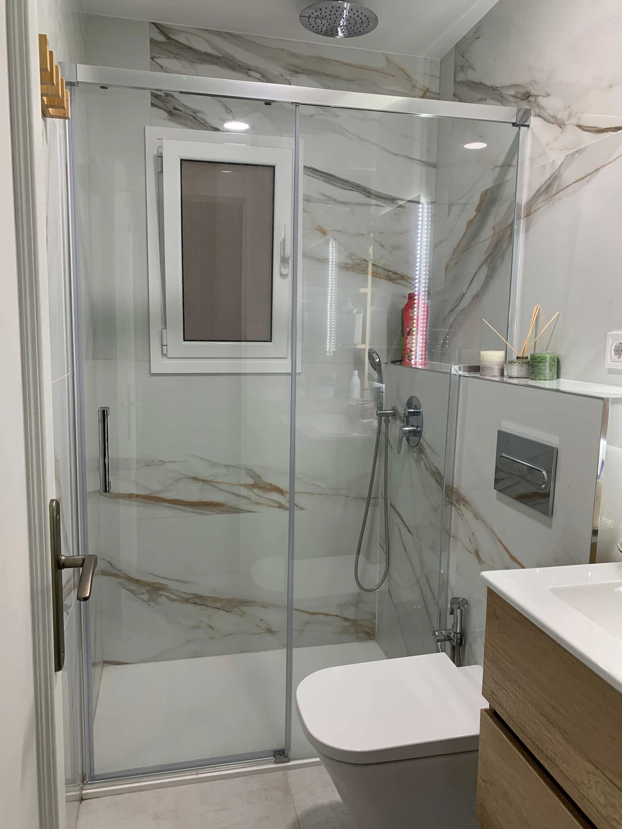 Ducha con mampara de cristal y azulejo efecto mármol